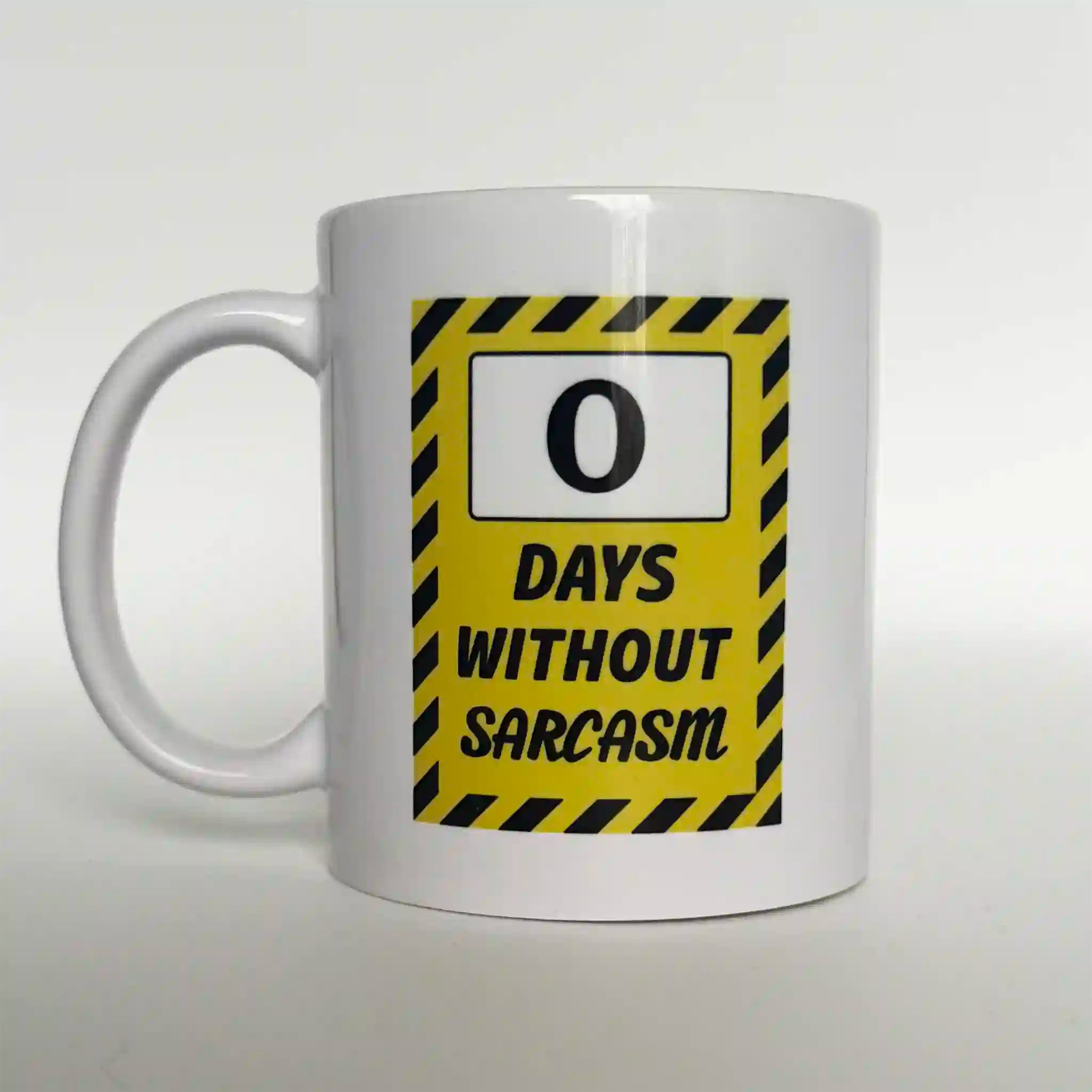 White ceramic coffee mug featuring a parody safety sign graphic that reads: "Zero Days Without Sarcasm." The funny office gift for coworkers, bosses, or sarcastic friends.
