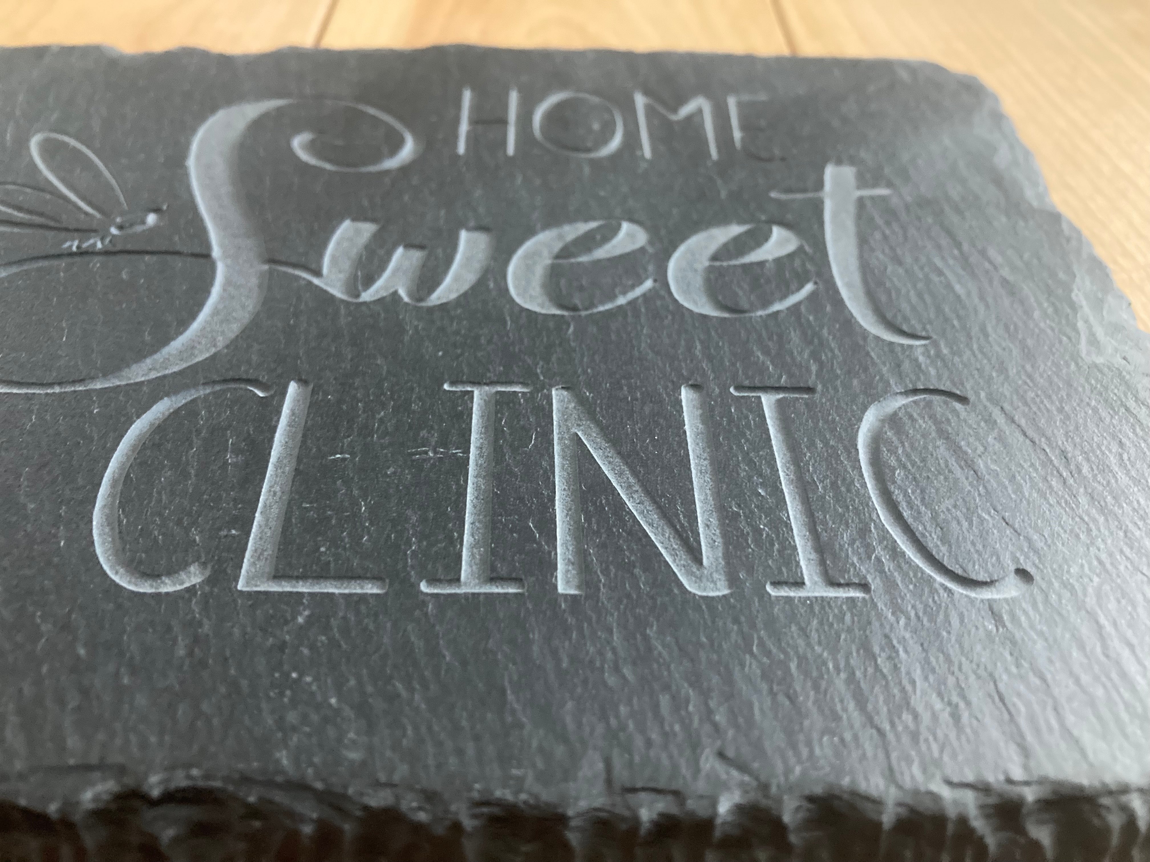 A closeup, front profile of Home Sweet Clinic sign with dragonfly. Showing the depth of the sand-carved slate sign.